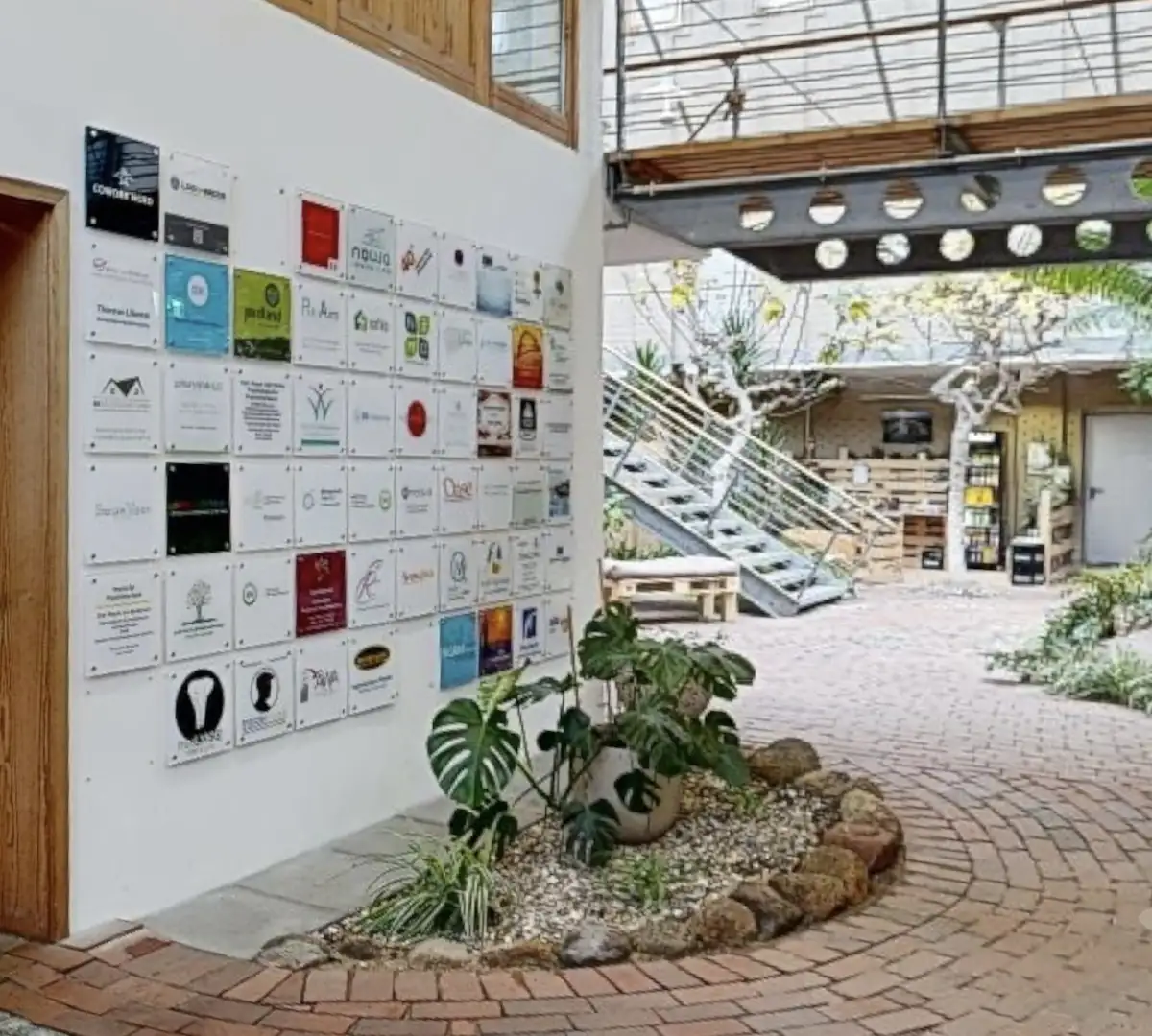 TÖZ Eckernförde – Eingangsbereich mit Firmenschilder-Wand, Monstera-Pflanze und Glasdach-Atrium