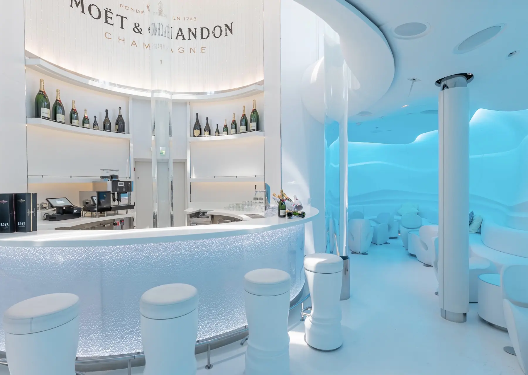 Weiße Bar und blau beleuchteter Loungebereich der Spray Bar by Moët & Chandon auf der AIDAperla