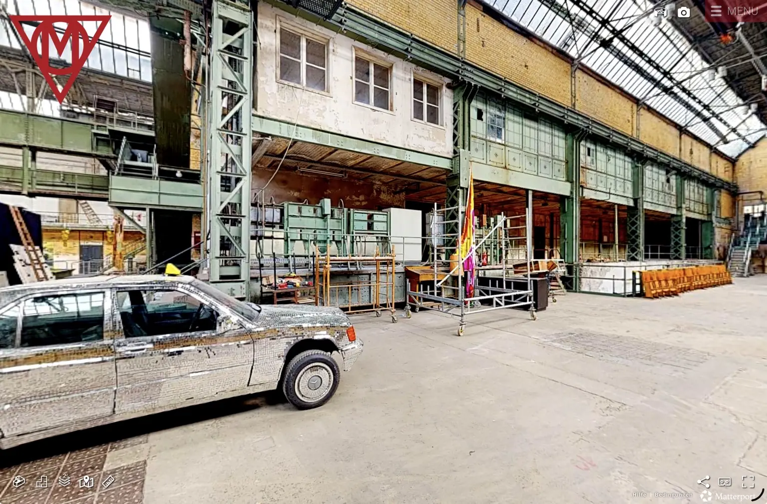 Produktions- und Ausstellungsbereich in der MaHalla mit historischem Stahltragwerk, Arbeitsplattformen und spiegelndem Fahrzeug