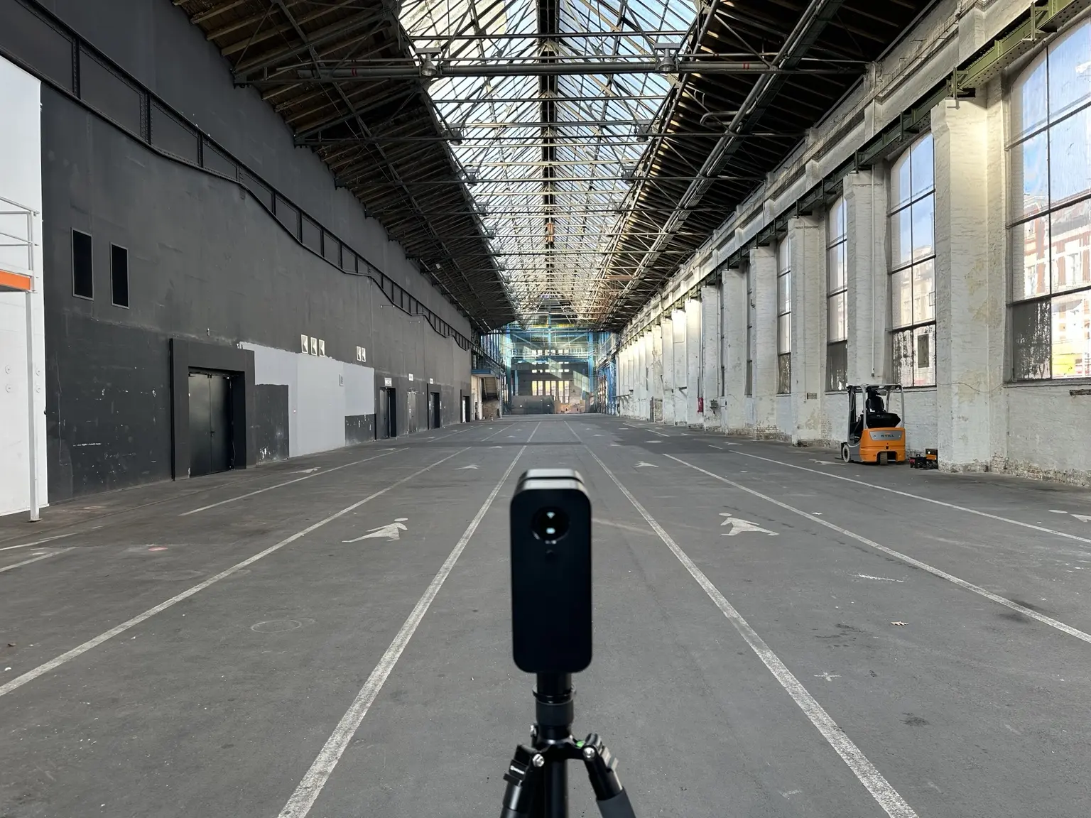 3D-Scanner auf der Mittelachse einer langgestreckten Halle unter dem filigranen Stahl- und Glasdach.