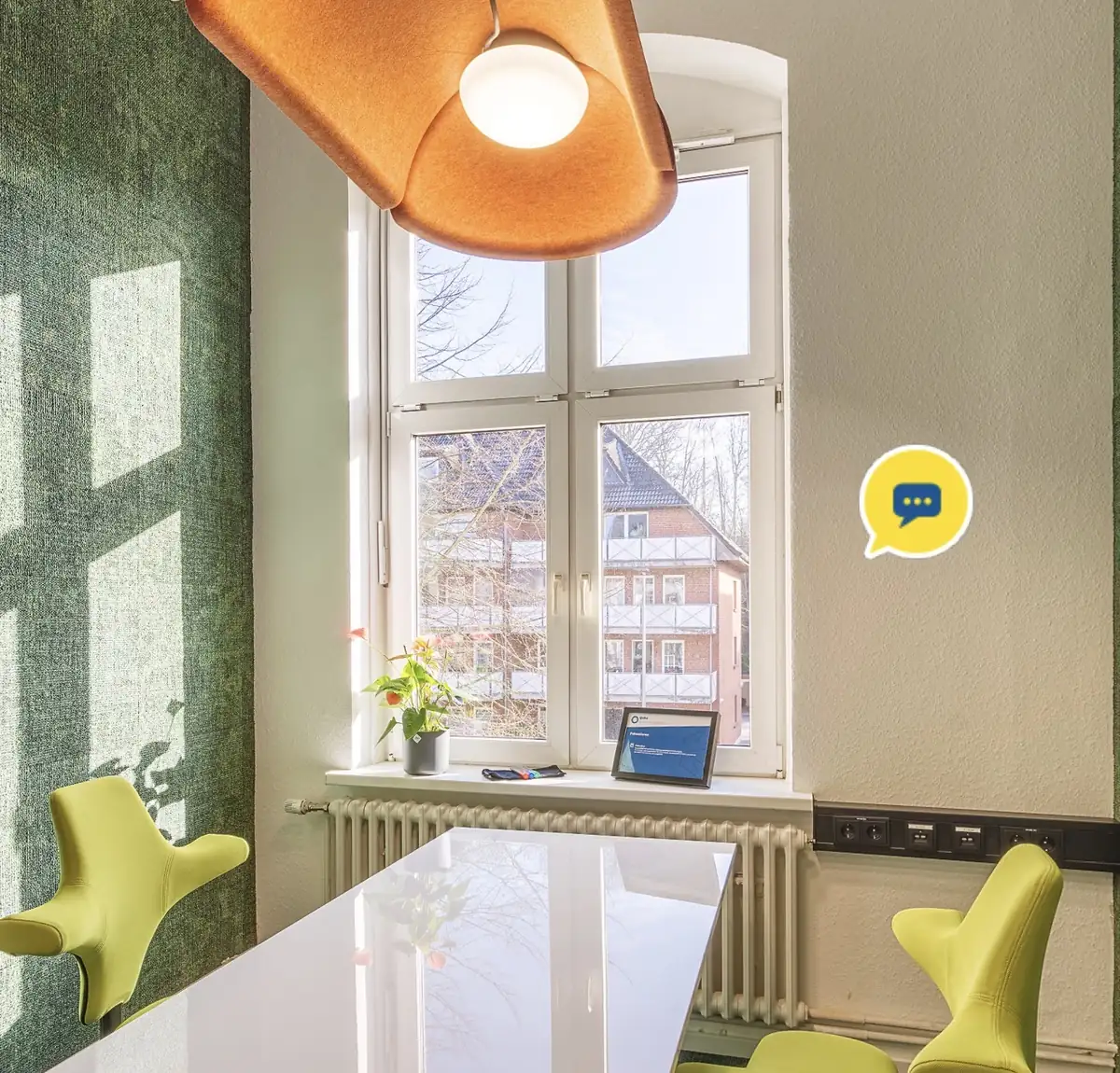 Besprechungsraum mit grüner Wand und gelben Stühlen im Qube