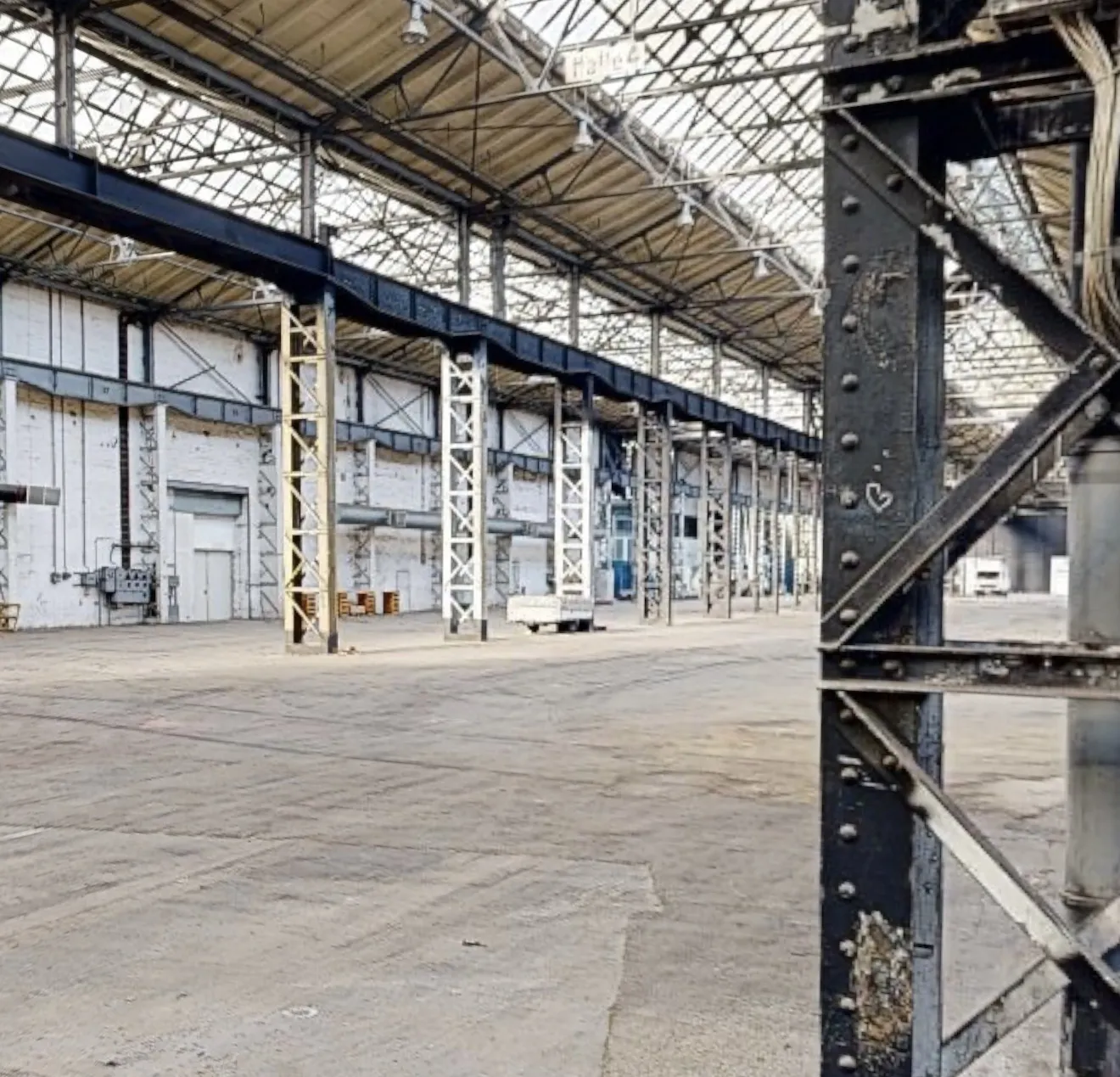 Detailaufnahme der Stahlkonstruktion einer Industriehalle – Stützen, Fachwerkträger und Kranschienen