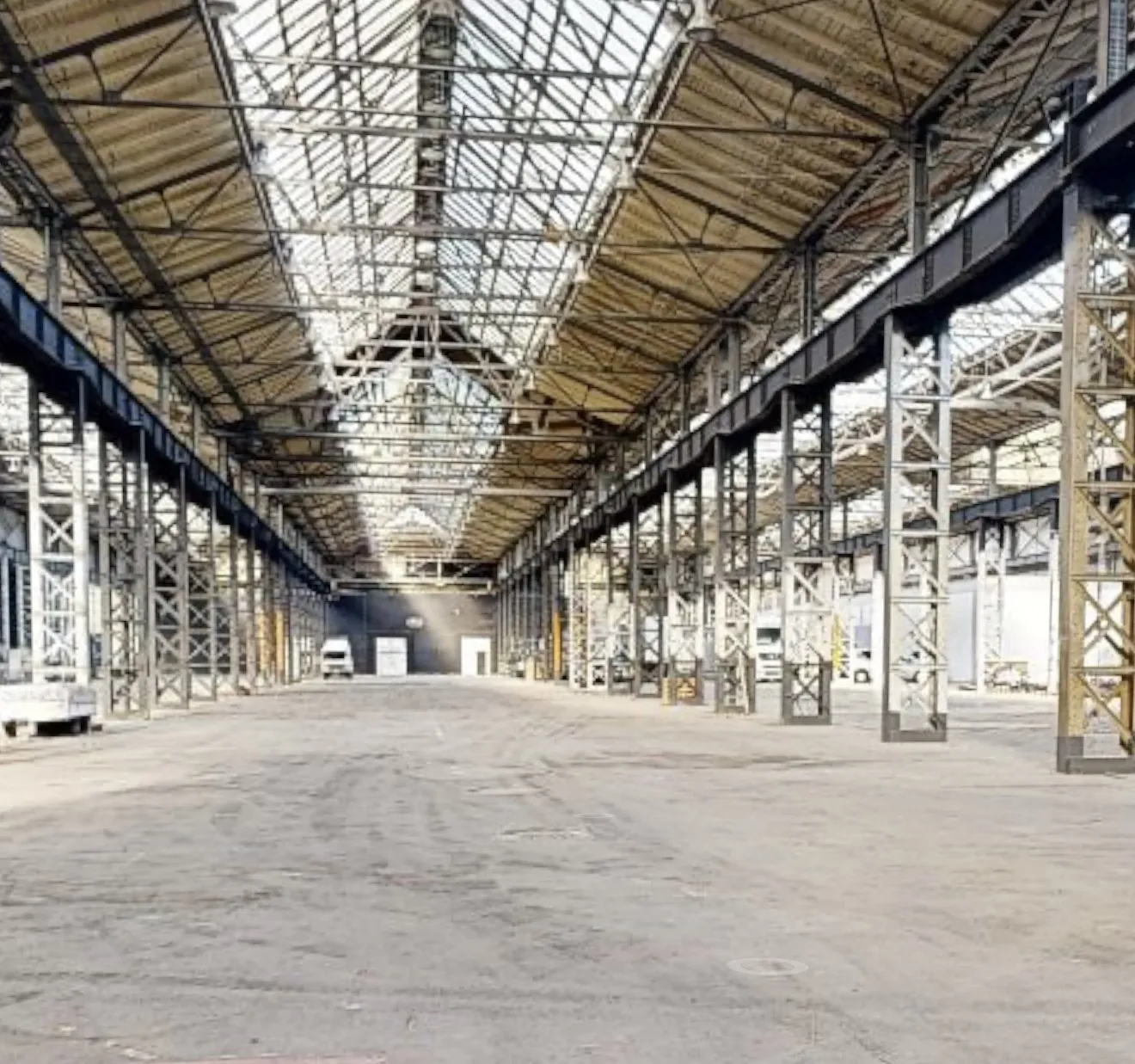 Weitwinkel-Innenansicht einer Industriehalle – Stahlträger, Dachkonstruktion und Hallenfläche