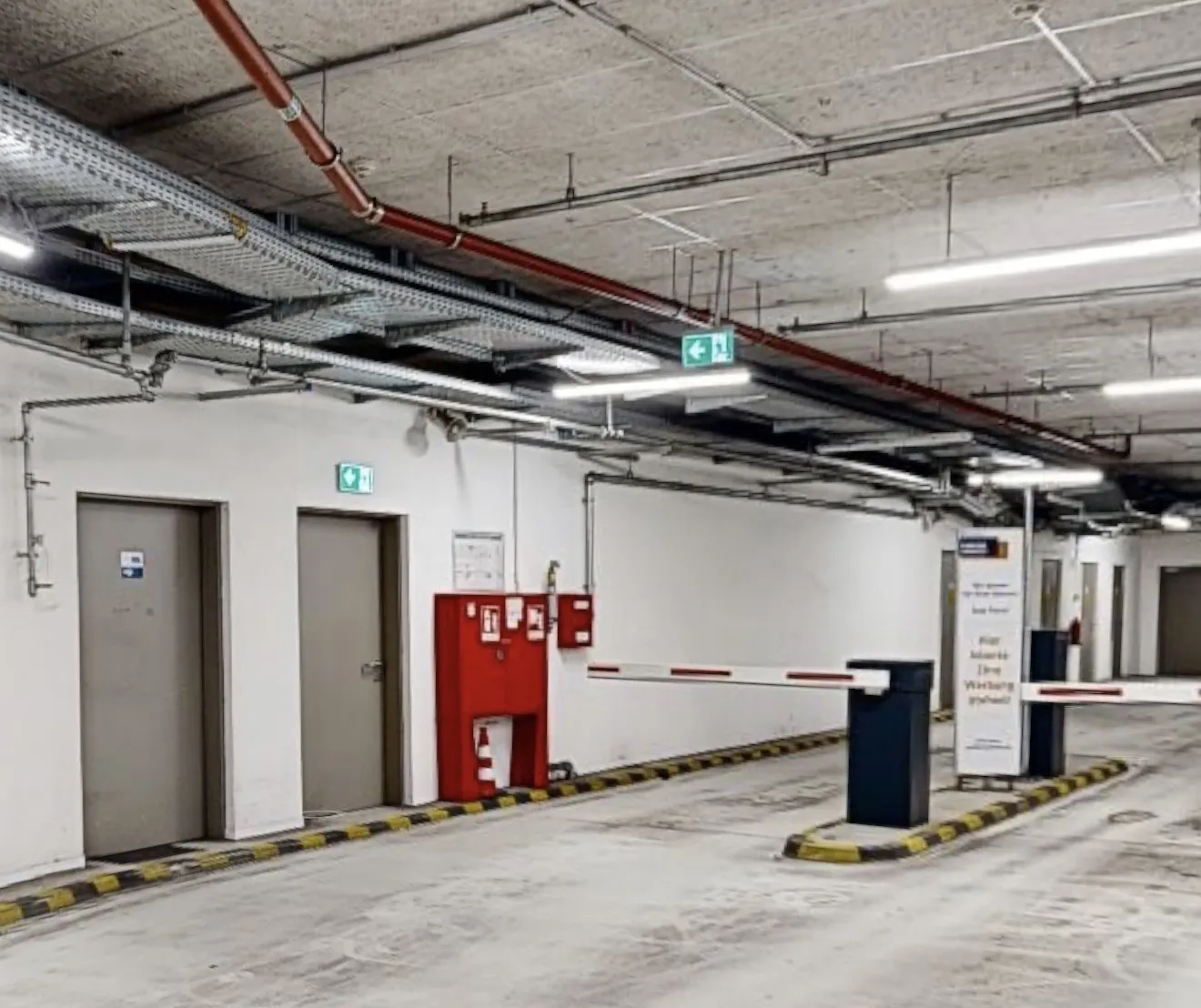 Schrankenbereich eines Parkhauses mit Brandschutzkasten und Rohrleitungen an der Decke
